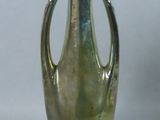 a green glass vase with a metal handle on a gray background