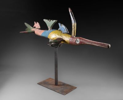 une photo représentant une sculpture d'oiseau colorée posée sur un socle en métal