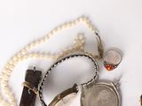 a lot of jewelry on a white surface including a watch, bracelet, ring, and other items