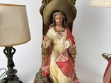 a statue of jesus sitting on a throne next to a lamp