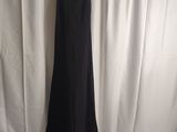 a black dress hanging on a hanger in front of a white curtain