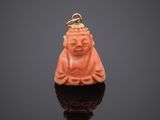 an orange jade buddha pendant on a black surface