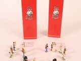 petites figurines représentant des personnes debout devant une boîte rouge
