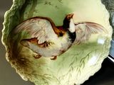 a plate with a bird painted on it next to a plate with a bird painted on it
