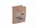 un livre marron orné d'oiseaux, posé sur une surface blanche