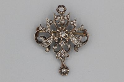 une broche en argent posée sur une surface blanche