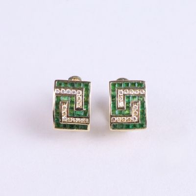 une paire de boucles d'oreilles en émeraude et diamant posées sur un fond blanc
