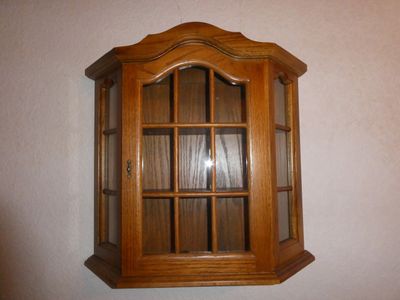 une armoire en bois avec une porte vitrée, fixée au mur