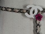 a white mannequin with a chain and a pink flower on it