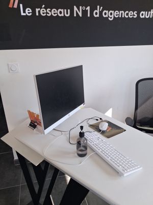un bureau blanc sur lequel se trouvent un clavier et un écran