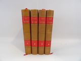 four brown books with red bindings are stacked on top of each other