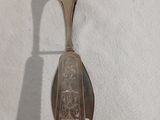 une cuillère en argent avec un manche sur une surface blanche