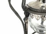a silver tea pot on a stand with a rope around it