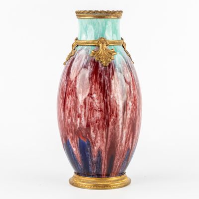 un vase coloré avec une anse dorée sur fond blanc