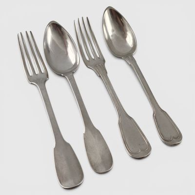 four silver spoons and a fork on a white surface