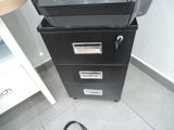 a black filing cabinet and a black bag on the floor