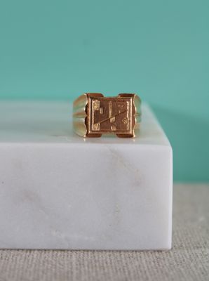 un gros plan d'une bague en or posée sur un bloc de marbre