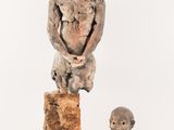 sculpture of a man sitting on a rock next to a busturine of a man