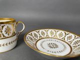 two white and gold cups and saucers on a table