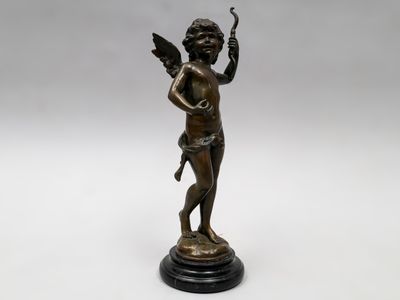 une statue en bronze représentant un Cupidon tenant un oiseau, posée sur un socle