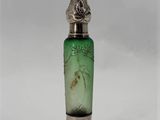 a green glass bottle with a silver lid on a white surface