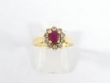 une bague en or jaune sertie d'un rubis entouré de diamants