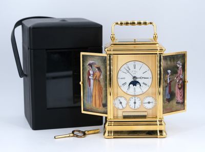 une horloge dorée ornée de motifs, à côté d'une boîte noire