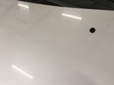 the hood of a white car with a hole in it