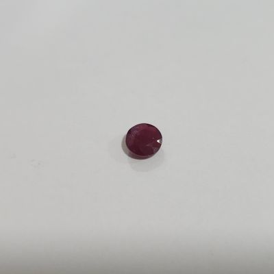 a single red ruby stone sitting on top of a white surface