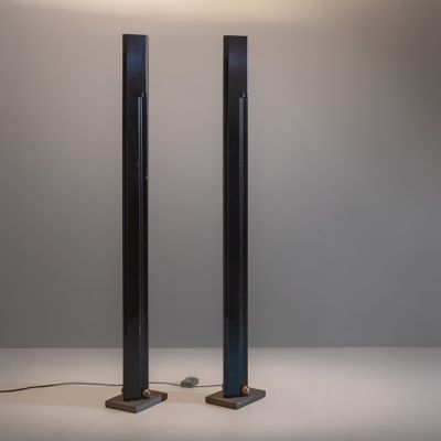 une paire de lampadaires en métal noir posés sur une surface blanche