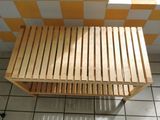 a wooden bench sitting on a tiled floor in a bathroom