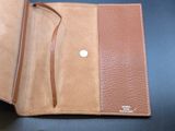 leather wallet with a small button on the inside of it on a table