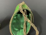 two green purses with beaded handles on a black surface