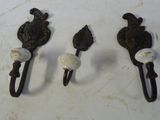 trois crochets muraux anciens en fonte sur un fond blanc
