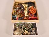 two boxes of assorted jewelry sitting on a table