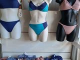 three mannequins are lined up on a shelf in front of a display of swimsuits