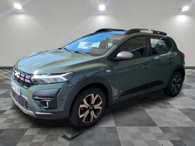 Une voiture verte est garée sur un sol à damier dans un garage.