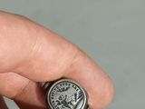 someone is holding a silver ring with a coin on it