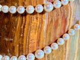 two strands of white pearls are on a wooden surface