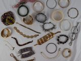 many different types of bracelets and rings laid out on a table