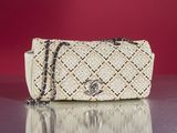 beige and black handbag with chain strap on a shiny surface