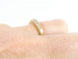 a woman ' s hand holding a gold ring with diamonds on it