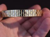 a person holding a gold and silver bracelet in their hand