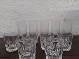 Quatre verres sont alignés sur une table, avec un mur blanc en arrière-plan.