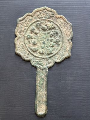 un vieux miroir en bronze orné d'un motif floral