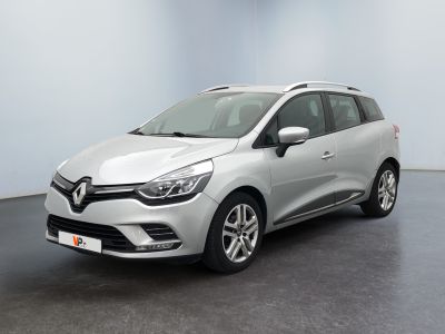 Une voiture argentée est garée dans une pièce au sol noir.