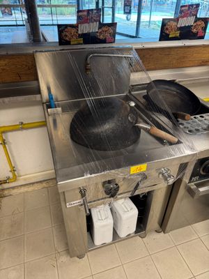 un plan de travail en acier inoxydable sur lequel sont posés des casseroles et des poêles, dans une cuisine professionnelle