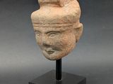 une ancienne tête d'homme sculptée dans la pierre, coiffée d'un chapeau