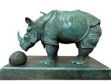 statue of a rhino with a ball on a pedestal