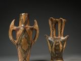 two brown vases sitting next to each other on a gray surface